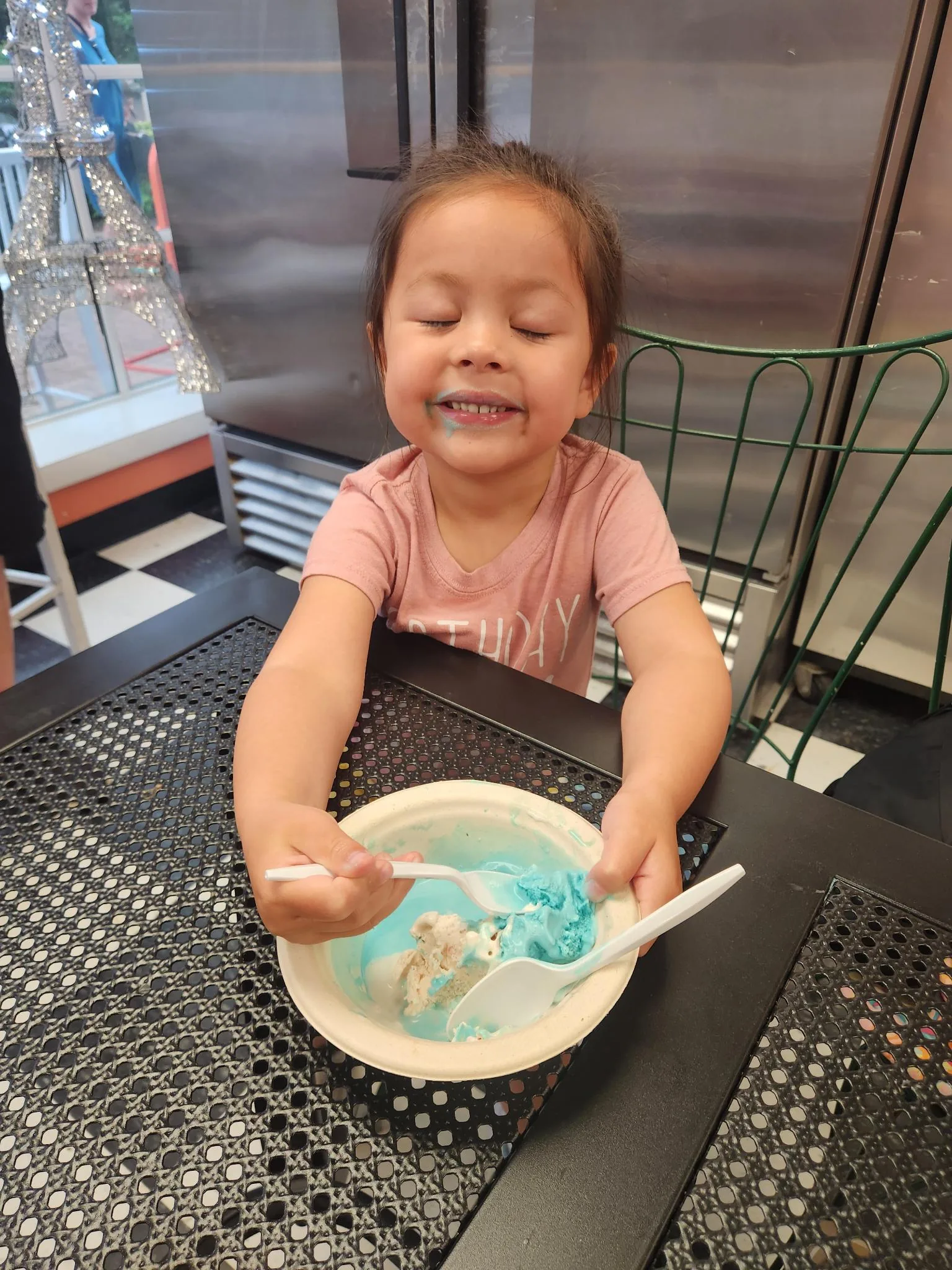 Young child happily finishing a bowl of blue ice cream