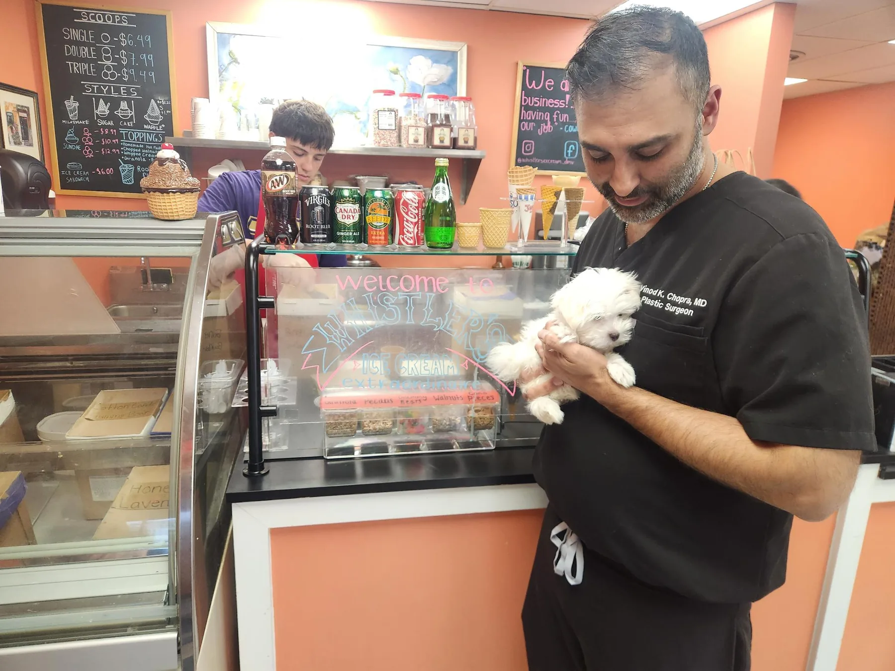 Customer holding a small white puppy at the Whistler's counter